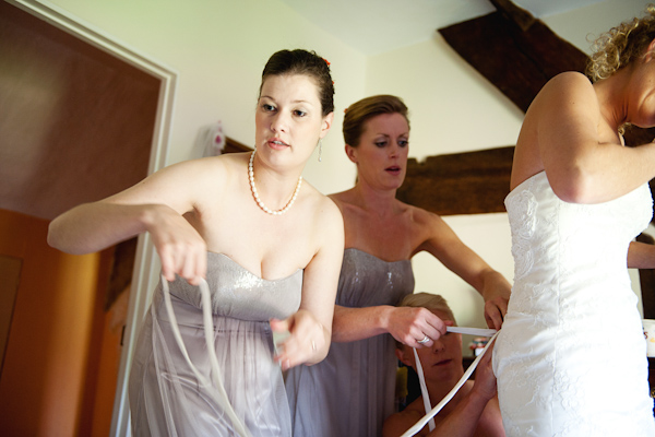 Bridesmaids helping put on dress